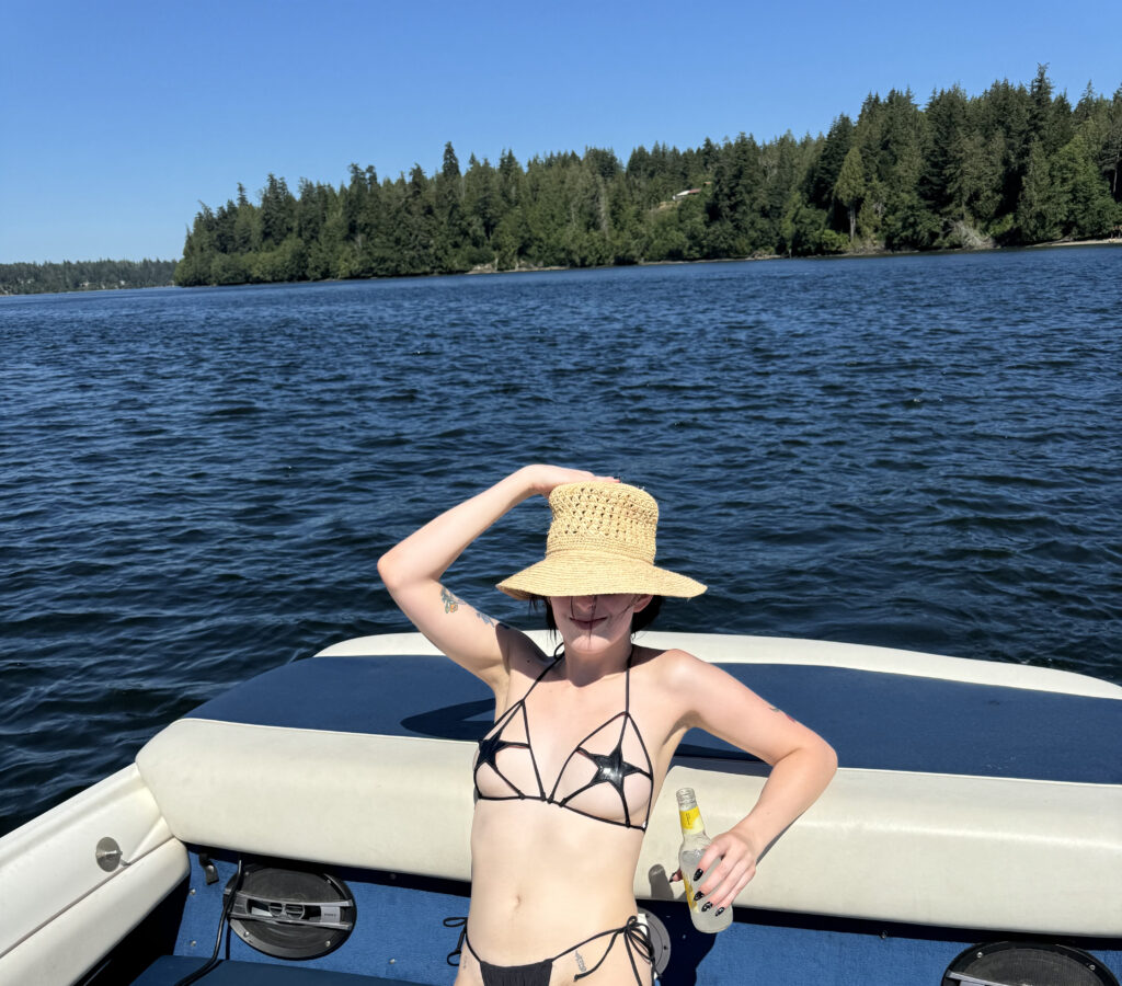 A photo from the waist up of me lounging on a boat in a star shaped PVC micro bikini.